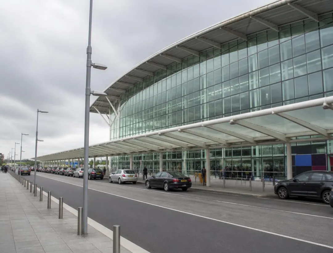 Heathrow Airport terminal with vehicles at the passenger drop-off area, representing private airport transfers from Berkshire.