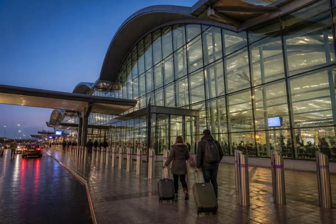 Passengers with luggage outside London Luton Airport terminal for a private transfer