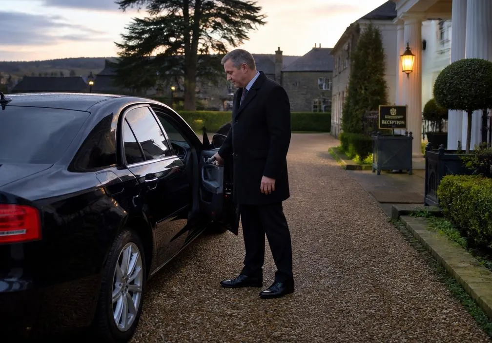 Chauffeur opening the door of a private hire car for a passenger pickup outside a hotel in Buckinghamshire