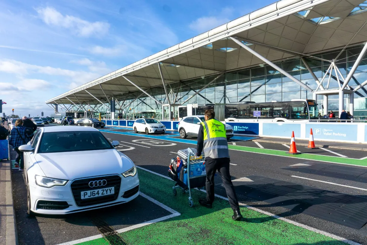 Passenger with luggage meeting a private hire car at Stansted Airport arrivals