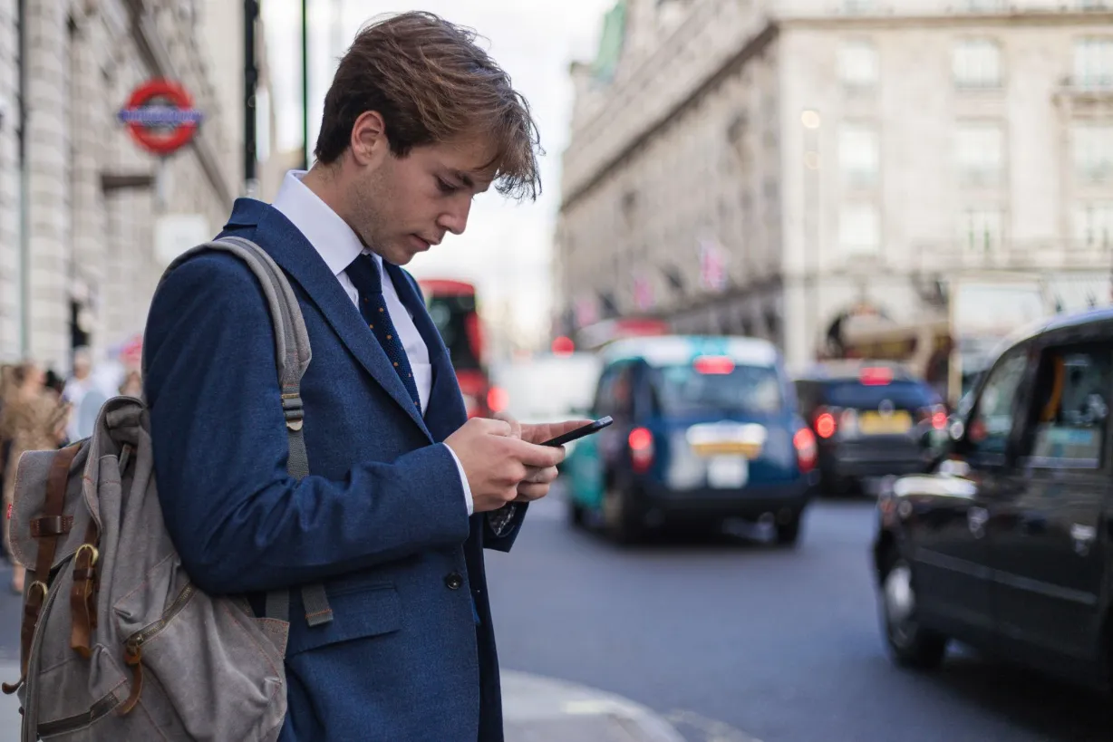 Passenger checking a phone while waiting for a taxi in London